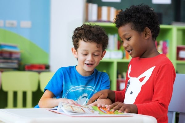 2 basisschoolkinderen bladeren samen door een boek