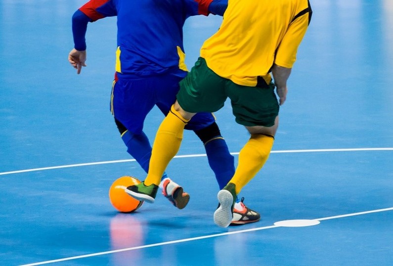 Twee zaalvoetbalspelers in een duel om de bal.
