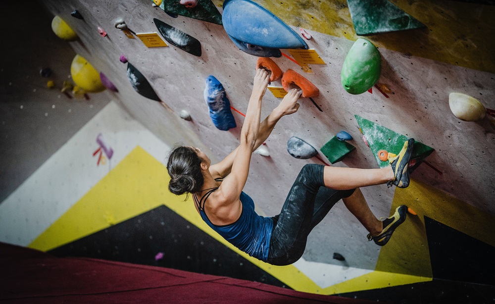 Een boulderaar kijkt omhoog en zet zich schrap voor de volgende pas.