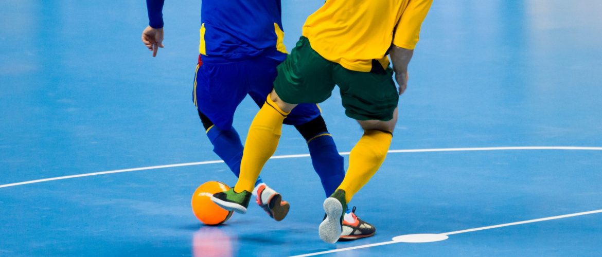 Twee zaalvoetbalspelers in een duel om de bal.