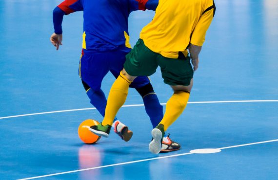 Twee zaalvoetbalspelers in een duel om de bal.